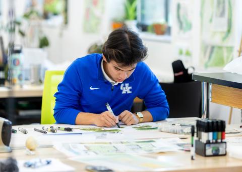 photograph of first year studio working on hand graphics wearing a uk half zip